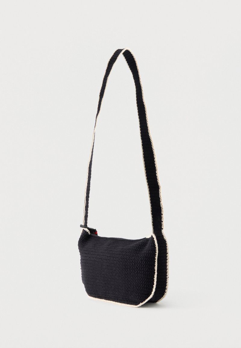 Black crochet crossbody bag with white edging and long strap, displayed against a plain light background.