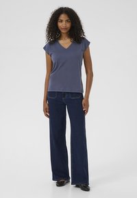 Mörkblå T-shirt med V-ringning och korta ärmar i mjukt tyg, kombinerad med vida blå denimjeans och svarta ballerinaskor. Enkel, avslappnad outfit.