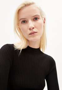 Schwarzer gerippter Rollkragenpullover mit tailliertem Design, langen Ärmeln und hohem Kragen. Glatte Textur und enganliegende Silhouette.