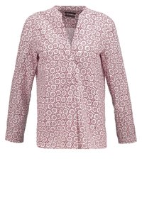 Blouse à manches longues blanche avec un motif en dentelle florale rouge, dotée d'un col en V et d'une fermeture à boutons, confectionnée en tissu léger.