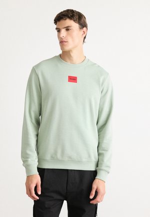 Mint green sweatshirt made of soft fabric, featuring a crew neck and ribbed cuffs. A small red square label with "HUGO" is on the front.
