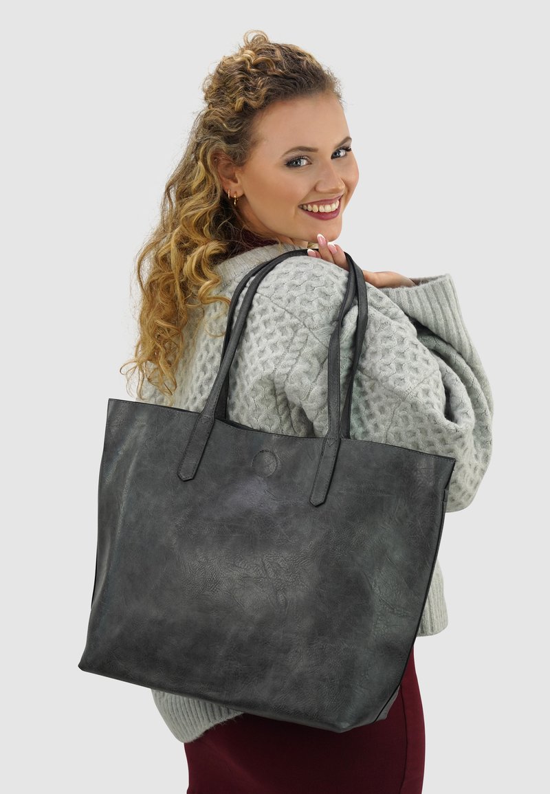 Grote grijze leren tote bag met twee lange hengsels, een gladde textuur, afgeronde hoeken en een subtiele gegraveerde patroon.