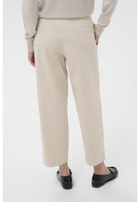 Beige capribyxor i lättviktsmaterial med två bakfickor och rak bendesign, tillsammans med svarta skor.