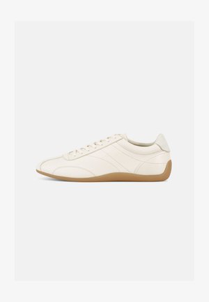 White leather sneaker with a smooth texture, rounded toe, and tonal stitching. Features a tan rubber sole and lace-up closure.