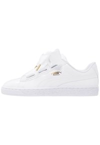 Bílé kožené tenisky s lesklým povrchem, bez tkaniček, s velkou látkovou mašlí, texturovanou gumovou podrážkou a zlatým logem jako akcentem.