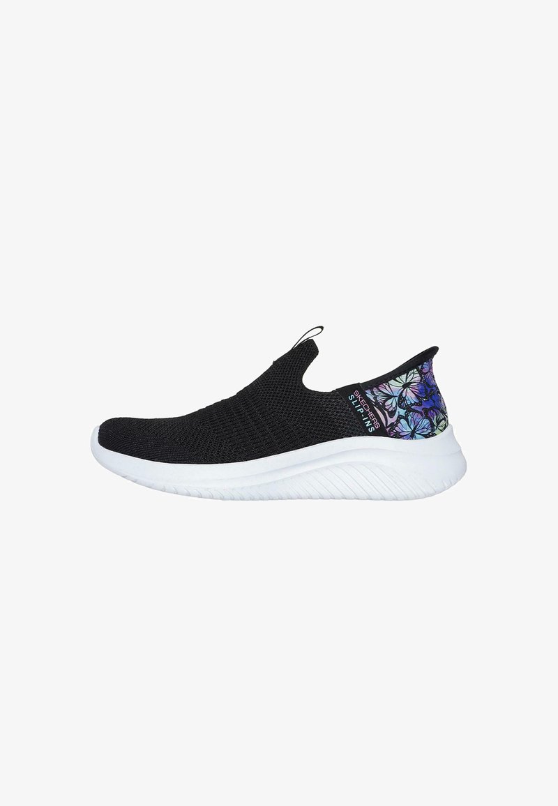 Zapatilla deportiva negra tipo slip-on con parte superior de punto texturizado, suela blanca y un patrón de mariposas de colores en el acento del talón. Diseño ligero y flexible.