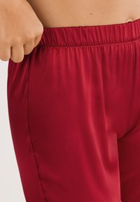 Rode satijnen joggingbroek met een elastische tailleband, met een gladde textuur en een aansluitende pasvorm, die zijnaad en een comfortabele fit laat zien.