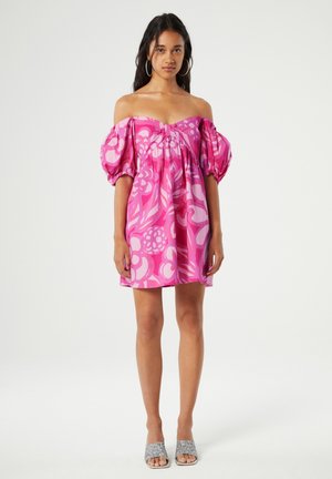Rosa schulterfreies Kleid mit großen puffärmel und Blumenmustern in verschiedenen Rosatönen. Getragen mit silbernen Riemchensandalen.