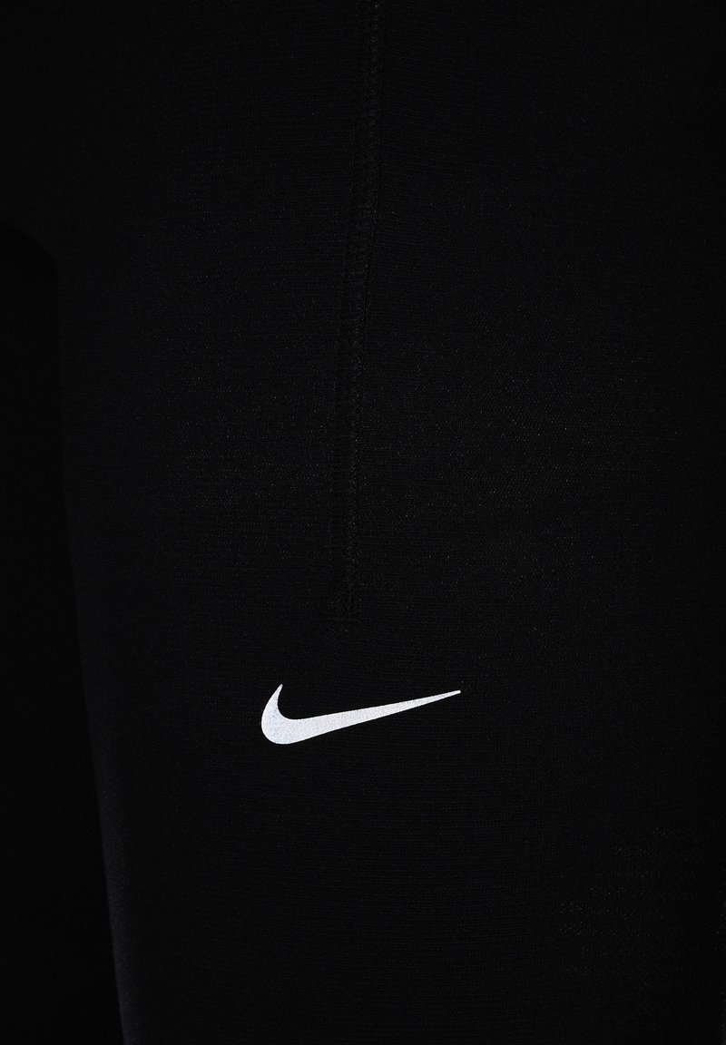 Leggings de sport noirs avec une texture lisse, comportant un logo Nike blanc près du bas à gauche. Les coutures plates mettent en valeur le design.