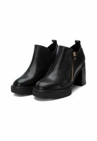 Botines de cuero negro con tacón ancho, cremallera lateral y suela texturizada negra. Acabado liso con paneles laterales elásticos para un mejor ajuste.