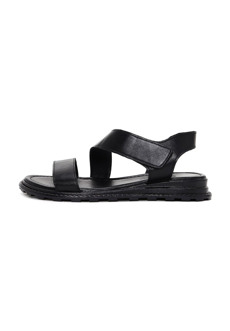 Sandali in pelle nera con cinturini incrociati, punta aperta e suola strutturata. Presentano un tacco basso e una costruzione flessibile per il massimo del comfort.