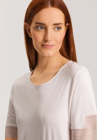 Top corto a maniche corte rosa chiaro con scollatura rotonda, caratterizzato da dettagli testurizzati sulle maniche e un materiale in cotone morbido e liscio.