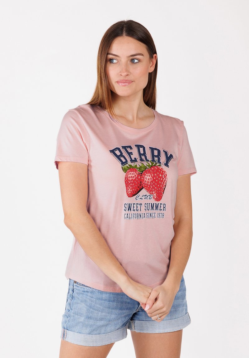 T-shirt en coton rose avec un graphique de deux fraises et le texte "BERRY CLUB SWEET SUMMER CALIFORNIA SINCE 1970". Manches courtes.
