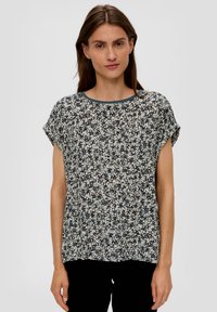Bluse mit Floralprint und kurzen Ärmeln. Weicher Stoff, runder Ausschnitt, dunkelblaue Basis und helle cremefarbene, beige und marineblaue Muster.