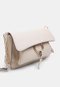 Borsa a tracolla in pelle beige con pattina piegata, hardware dorato, accent circolare e tracolla a catena, caratterizzata da una finitura testurizzata e bordi a contrasto.