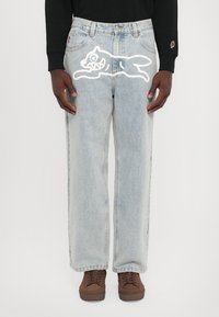 Light blue denim jeans with a relaxed fit, featuring a white cartoon cat design on the right thigh and a standard five-pocket layout.