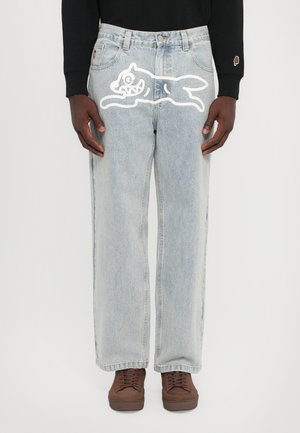 Lyseblå denimjeans med en avslappet passform, med et hvitt tegneserie-kattedesign på høyre lår og en standard fem-lommers layout.