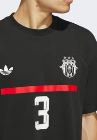 Black t-shirt with a round neckline, featuring a white Adidas logo, a red horizontal stripe, and the number 3 in white, with a basketball emblem.