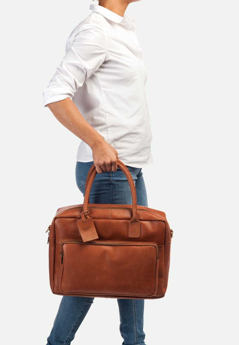 Bruine leren laptoptas met twee handvaten aan de bovenkant, een voorste ritsvak en een bagagelabel. Kenmerkt een gladde, gestructureerde afwerking en rechthoekige vorm.