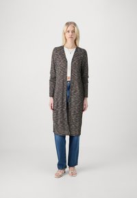 Cardigã longo e aberto à frente em tecido texturizado multicolorido, com mangas longas e um ajuste descontraído. Combinado com jeans azuis de cintura alta.