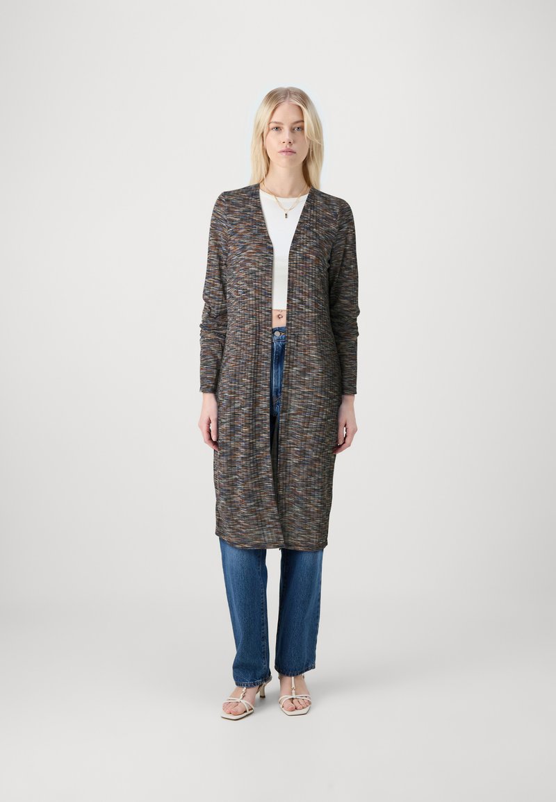 Cardigã longo e aberto à frente em tecido texturizado multicolorido, com mangas longas e um ajuste descontraído. Combinado com jeans azuis de cintura alta.