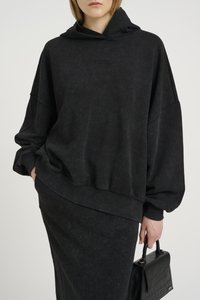 Musthave suurrihm, must, kohmakas, tekstuuriga viimistlusega, laiad varrukad ja soonikkoes mansetid; kantud sobiva seeliku ja musta käekotiga.