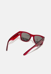 Ochelari de soare din plastic roșu cu lentile gri închis. Design unghiular cu rame groase și brațe subțiri. Dotati cu accente metalice la balamale.