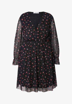 Mustapuku, jossa on V-pääntie, läpinäkyvät pitkät hihat ja joustava vyötärö. Kuvioitu punaisilla sydämillä ja valkoisilla pisteillä tummalla taustalla.