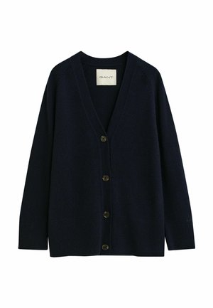 Cardigan en laine marine avec un décolleté en V profond, fermeture à six boutons, bord côtelé et texture subtile. Étiquette logo affichée sur le col.