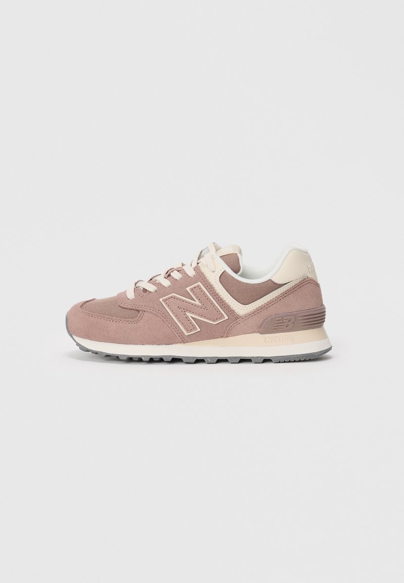 Light pink suede sneakers with cream accents, featuring a textured fabric upper, flat laces, and a rubber sole with tread pattern.