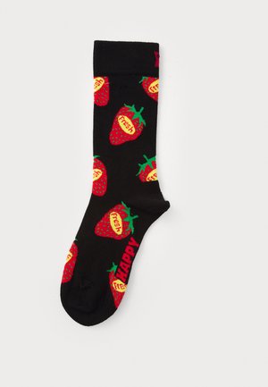Chaussettes noires avec un motif de fraises répétées en rouge et vert, portant le mot "frais" en jaune sur chaque baie. Le mot "HEUREUX" est en rouge.