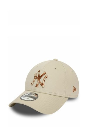 Beige Baseballcap mit gebogenem Schirm, ausgestattet mit einem braunen gestickten "NY"-Logo und einem kleinen braunen Akzent an der Seite, aus Stoffmaterial gefertigt.