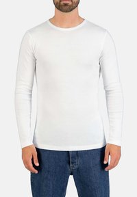 Weißes langärmliges T-Shirt aus weichem Stoff, mit einem runden Ausschnitt und taillierter Passform, kombiniert mit blauen Jeans.