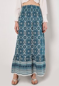 Maxikjol i blått och vitt med intrikata blommönster och geometriska mönster. Resårlinning, flödande tyg, ankellång design.