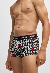 Boxers negros con diseño de logo "HUGO" en blanco y rojo, con una cinturilla suave marcada con el nombre de la marca.