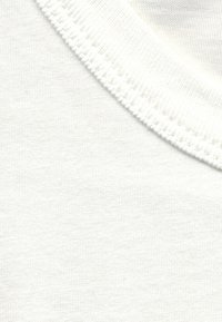 White cotton fabric featuring a smooth texture, with a ribbed crew neck and fine stitching along the edges.