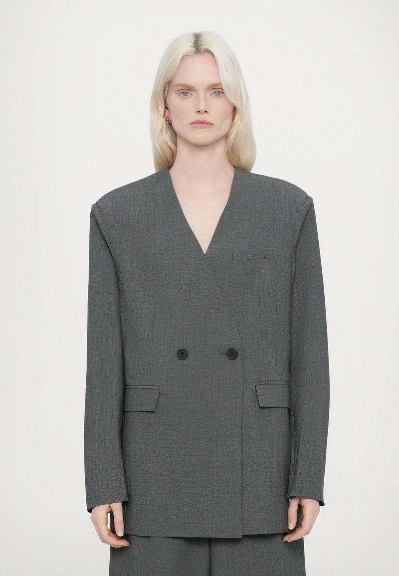 Blazer doppiopetto in tessuto grigio medio con finitura a trama, caratterizzato da scollo a V, due tasche frontali e bottoni neri.