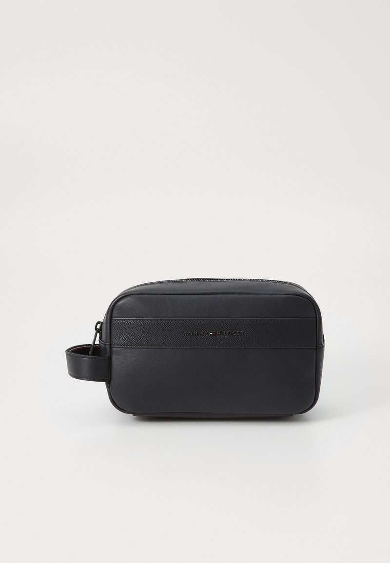 Black toiletry bag made of smooth leather with a zip closure, side handle, and understated logo detailing on the front.