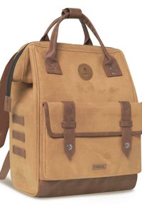 Sac à dos en toile marron avec des accents en cuir, poignées supérieures et rabat avant. Il présente un logo circulaire et des sangles latérales verticales pour l'attache.