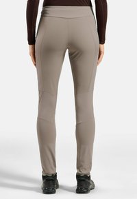 Eng anliegende, hellbeige Sportleggings mit Hohem Bund, nahtlosen Seiten und kontrastierenden strukturierten Einsätzen, kombiniert mit schwarzen Sportschuhen.