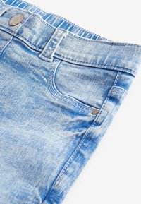 Ljust blå denimjeans med en blekt tvätt, med knappstängning, fem fickor och kontrasterande sömmar.
