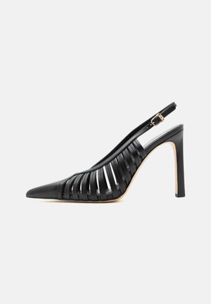 Fekete magas sarkú slingback cipő hegyes orral és kivágott bőrpántokkal, arany csattal a bokapánton.