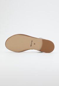 Nahka-sandaalin pohja, jossa on sileä beige pinta, vaaleanruskea kanta ja leimattu teksti "VALMISTETTU ITALIASSA" sekä koko "37".