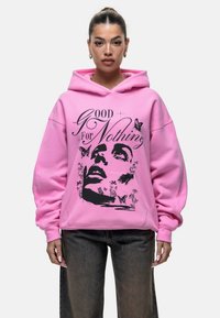 Felpa oversize rosa con un design grafico che presenta il volto di una donna, farfalle ed elementi floreali stampati in nero.