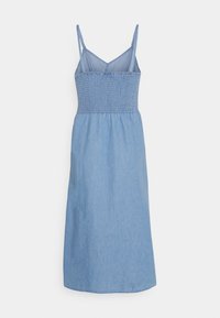 Abito in denim senza maniche di colore blu chiaro. Presenta un corpetto arricciato e una gonna fluida, con spalline regolabili e lunghezza fino al polpaccio.