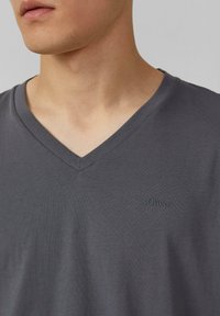 Szara koszulka z krótkim rękawem typu V-neck, wykonana z gładkiej bawełny, z dyskretnym haftem logo na lewym piersi.