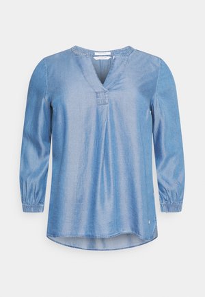 Lichtblauwe blouse met lange mouwen, V-hals, geplooide manchetten en licht gebogen zoom, afgebeeld op een witte achtergrond.