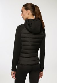 Czarna kurtka z ocieplanym tyłem i kapturem, gładkim przodem, długimi rękawami oraz dopasowanym krojem, zaprojektowana dla wygody i ciepła.