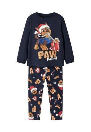Pyjama enfant bleu marine avec un chien de la Pat' Patrouille portant un chapeau de Père Noël sur le haut et un motif festif de chiens, cannes en sucre d'orge et flocons de neige sur le pantalon.