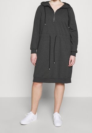 Robe sweat à capuche grise avec une encolure zippée, des poches latérales, une taille avec cordon de serrage et des poignets côtelés, associée à des baskets blanches.